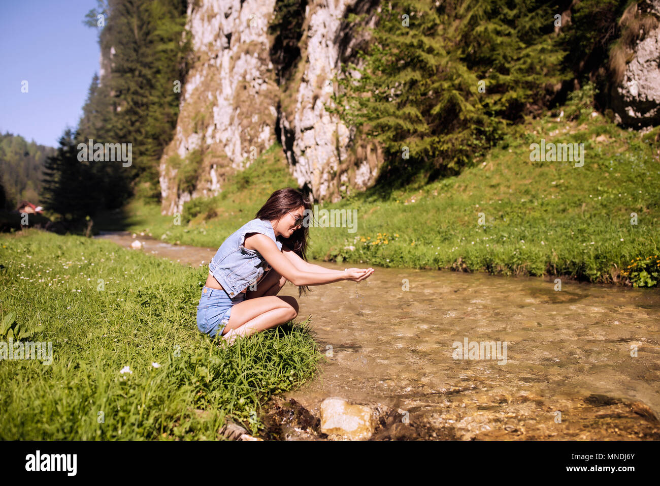 A beautiful tourist enjoys nature next to a mountain river Stock Photo