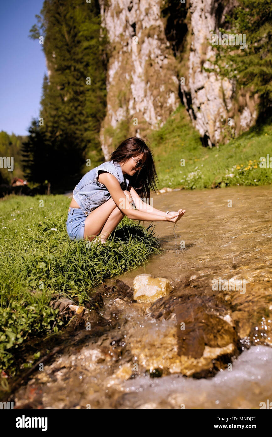 A beautiful tourist enjoys nature next to a mountain river Stock Photo