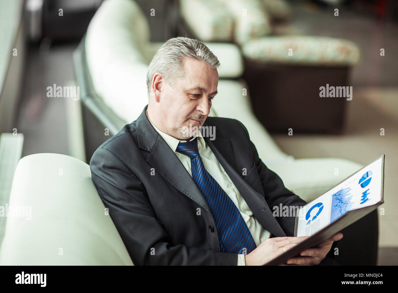 experienced financier with financial charts sitting in the chair in front of the office. Stock Photo