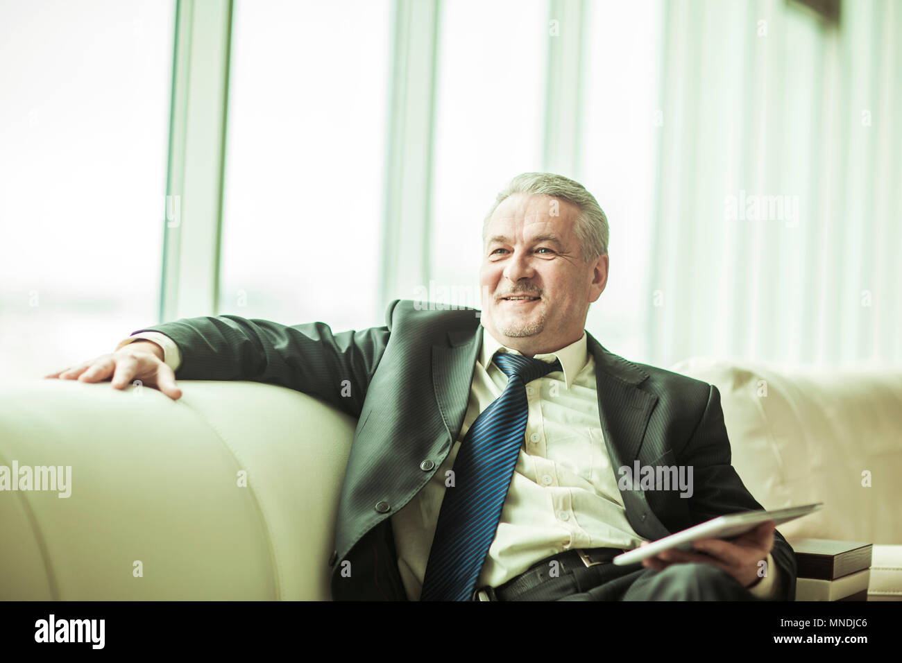 experienced lawyer with digital tablet sitting on the sofa in the private office Stock Photo
