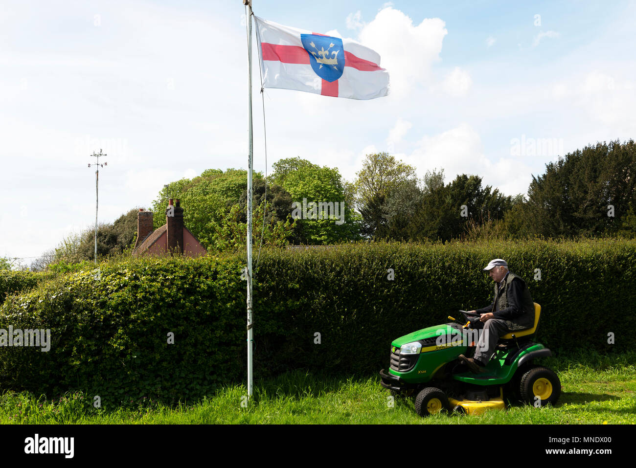Old age pensioner using a ride-on lawn mower, Bawdsey, Suffolk, England. Stock Photo