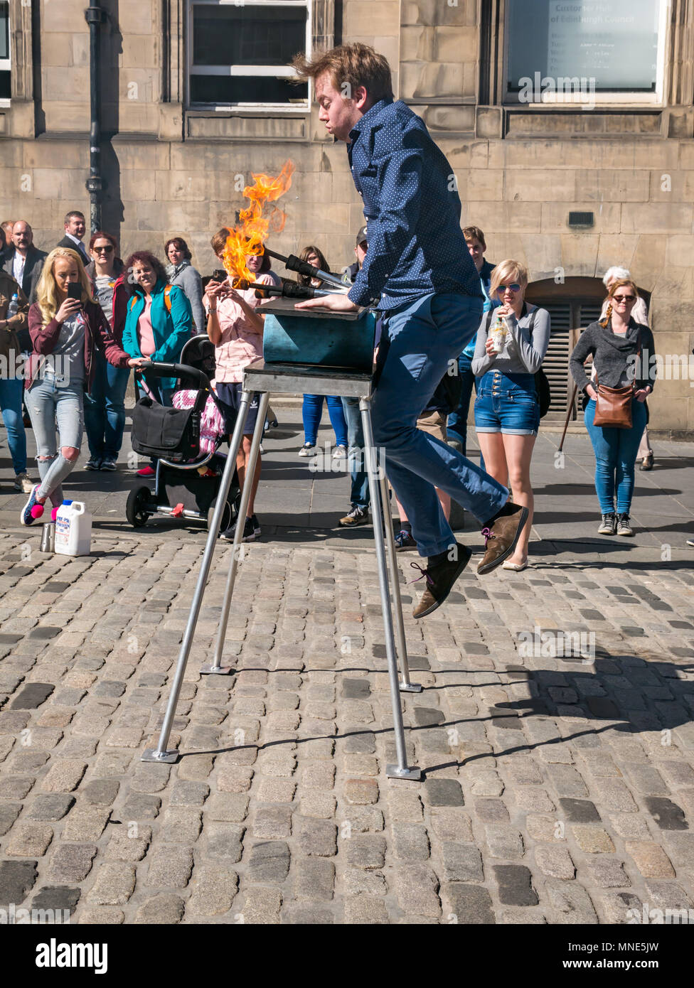 Royal Mile, Edinburgh, 16th May 2018. Tourists enjoying the sunshine and street entertainment on the Royal Mile, Edinburgh, Scotland, United Kingdom. Tourists watch a street performer called Daniel, whose act includes juggling flaming torches and large knives and machetes Stock Photo