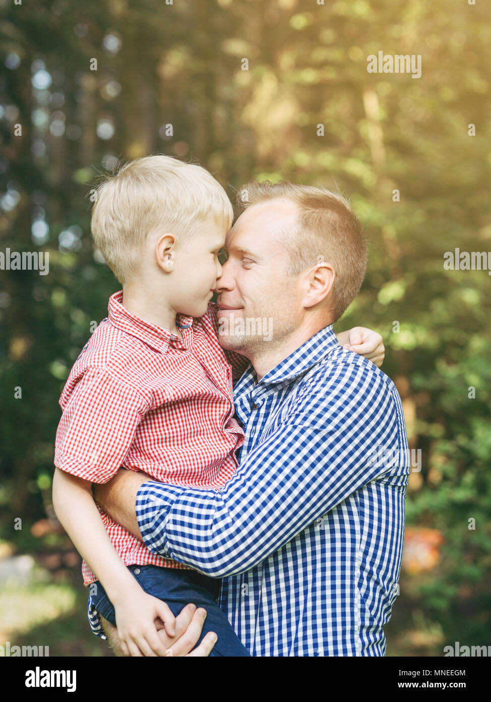 Gentle embrace of father and son in the park. Masculinity concept. Blondy people. Family, love. Stock Photo