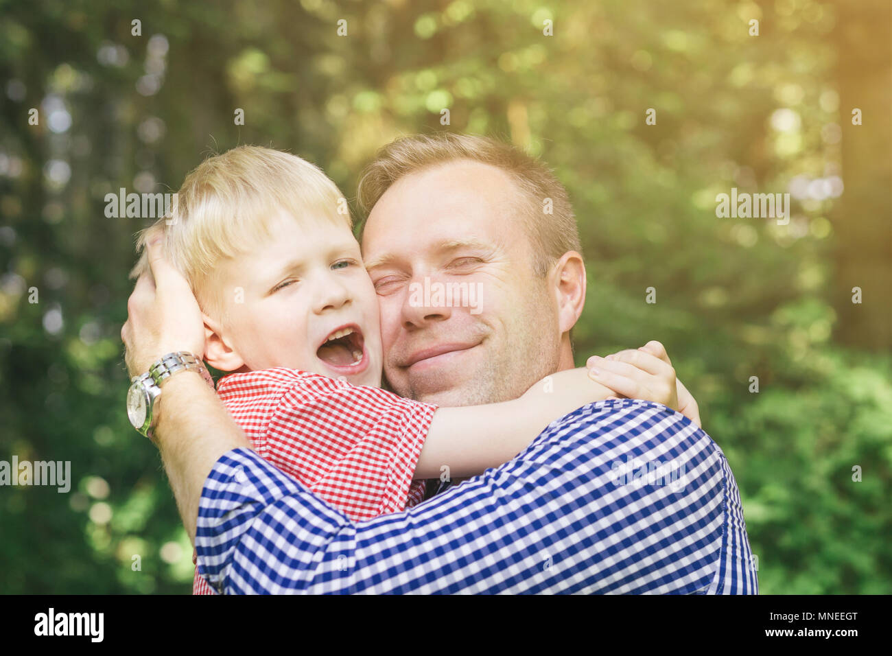 Father and son hugging and smiling. Child screaming with joy. Masculinity concept. Blondy people. Family. Stock Photo