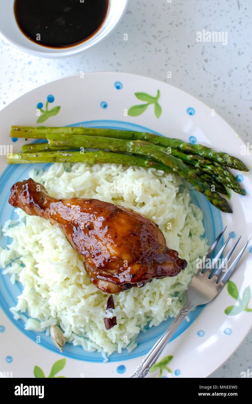 Teriyaki chicken drumsticks served with white rice on white table Stock Photo