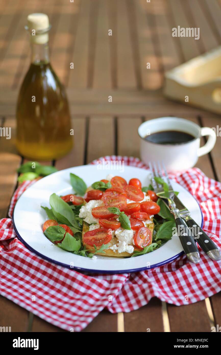 Bruschetta with ricotta cheese, cherry tomatoes and basil served in garden Stock Photo