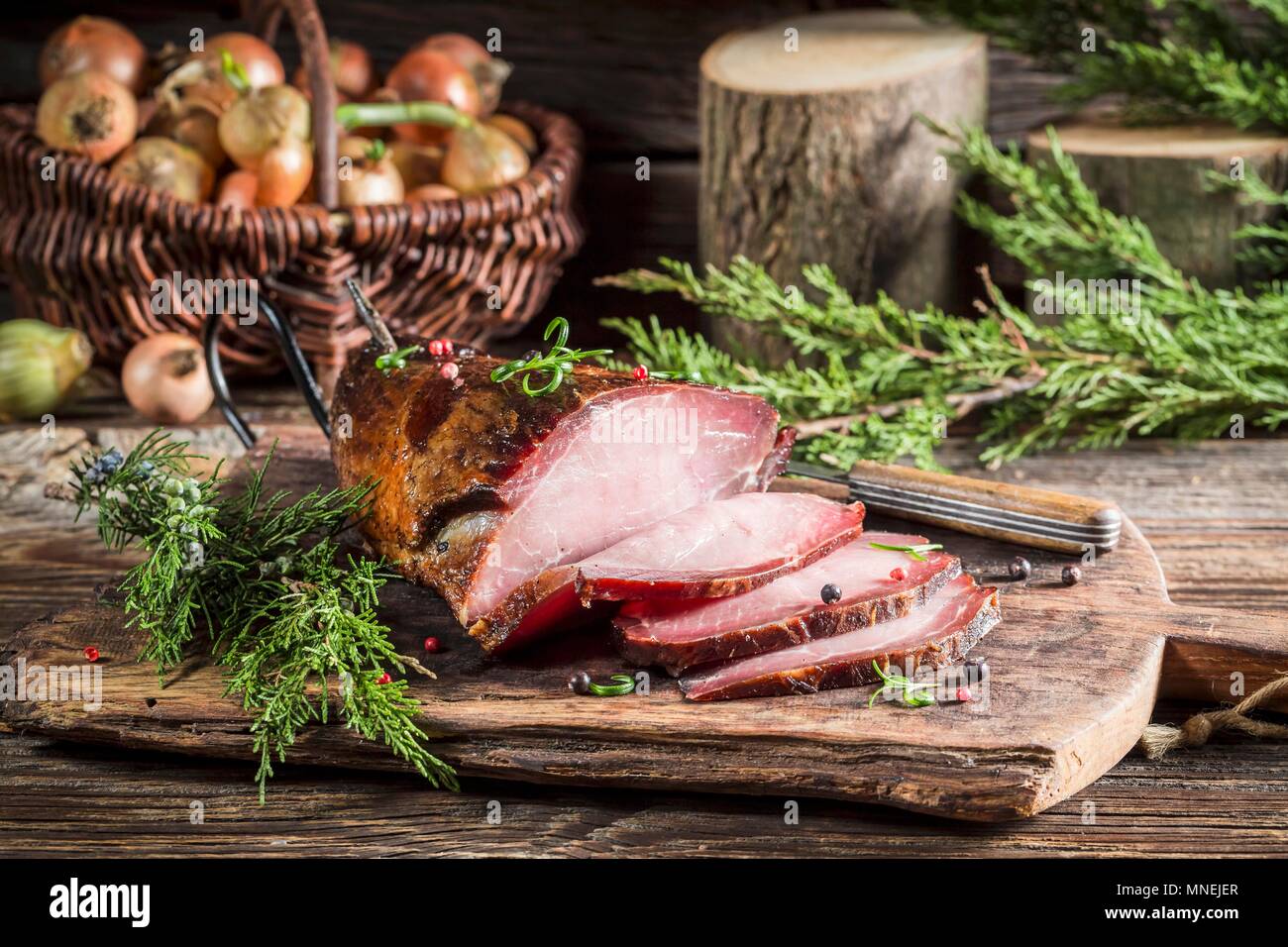 Smoked ham with juniper berries on a wooden chopping board Stock Photo