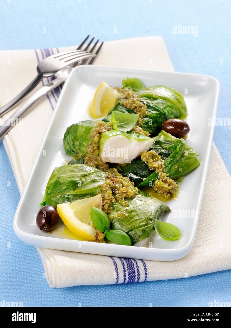Hake and lettuce rolls with a green olive sauce and lemons Stock Photo