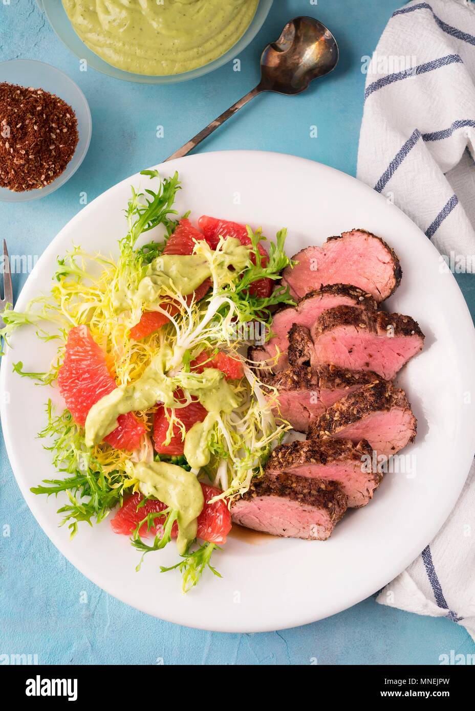 Healthy pork dinner with grapefruit and frisee on white plate Stock Photo