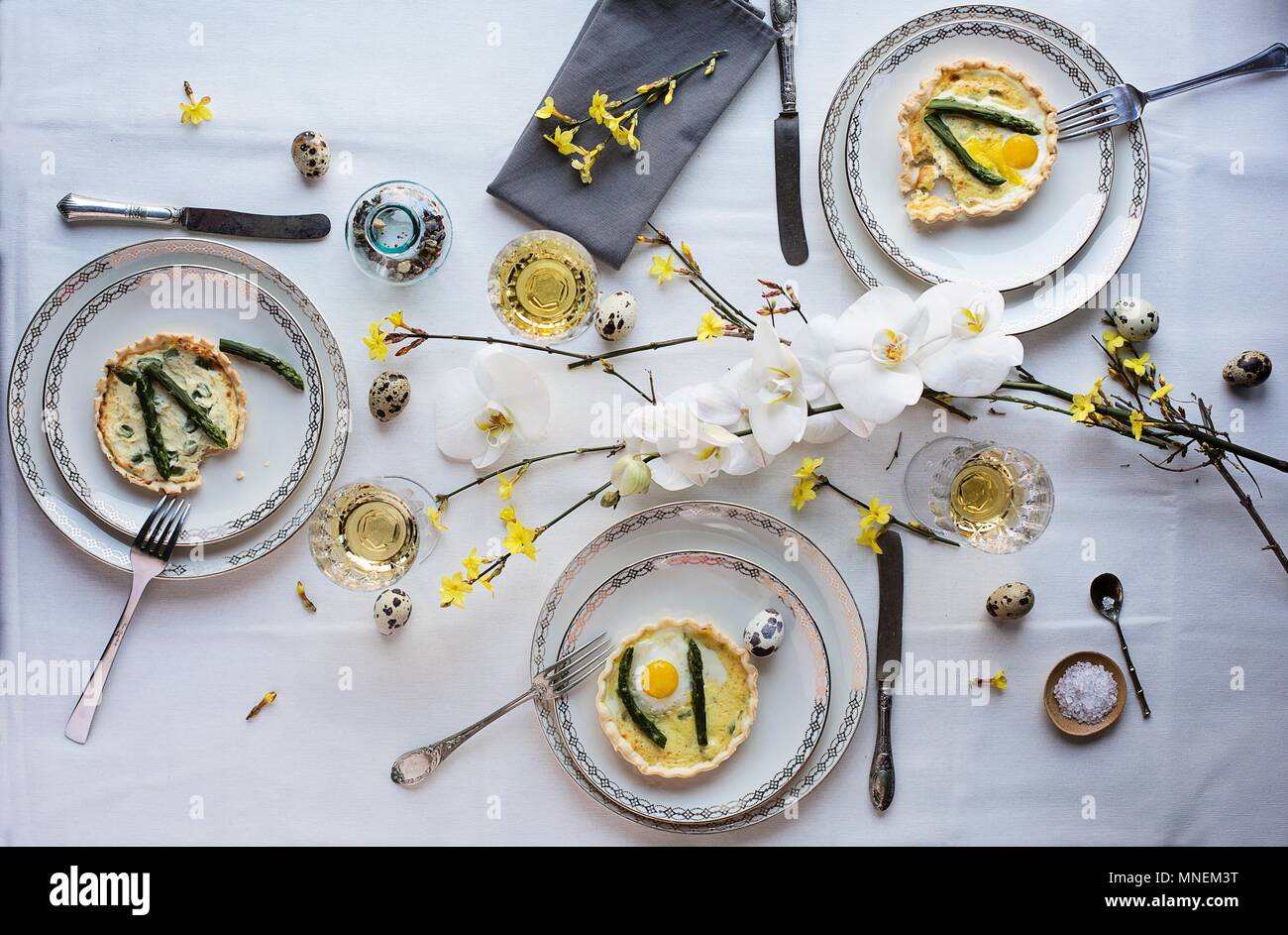 Asparagus quiche with fried quail egg on a dining table set for Easter