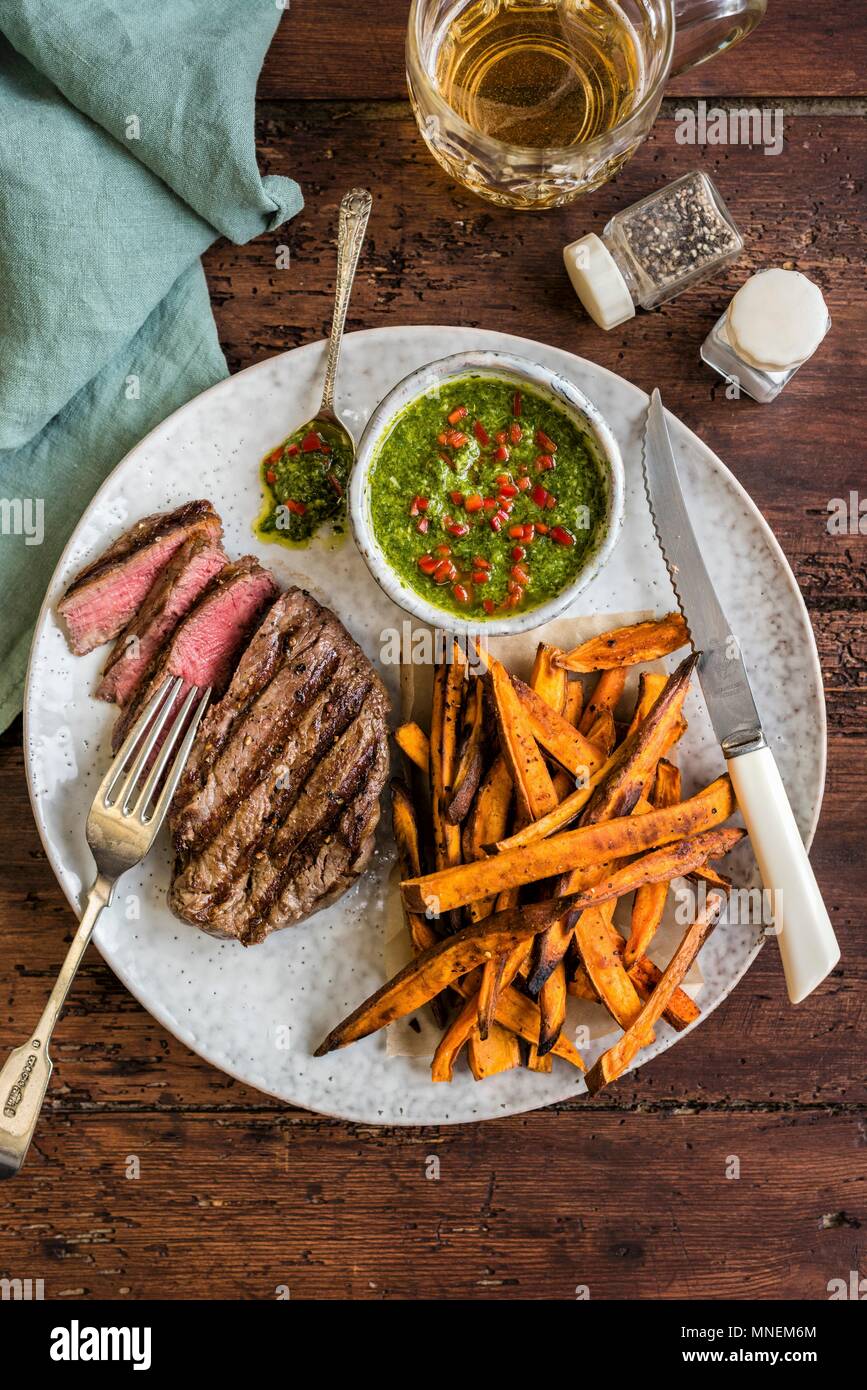 Griddled fillet steak with sweet potato fries and chimichurri sauce Stock Photo