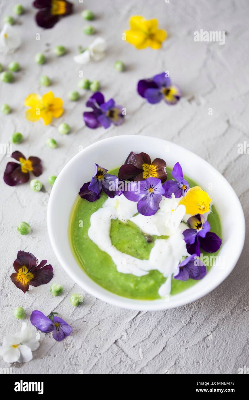 Cream of green pea soup with sour cream and edible flowers Stock Photo