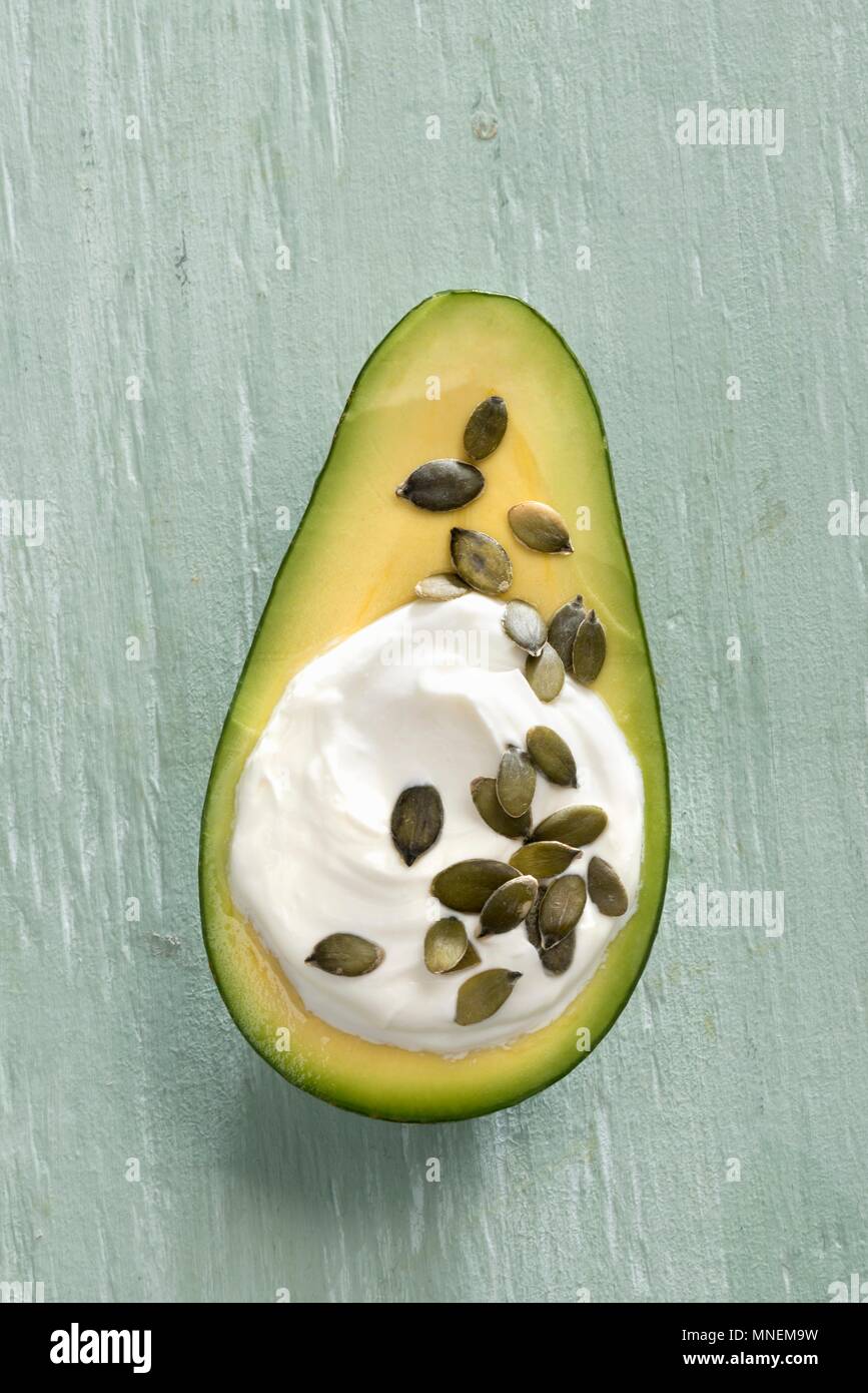 An avocado filled with Greek yoghurt and pumpkin seeds Stock Photo