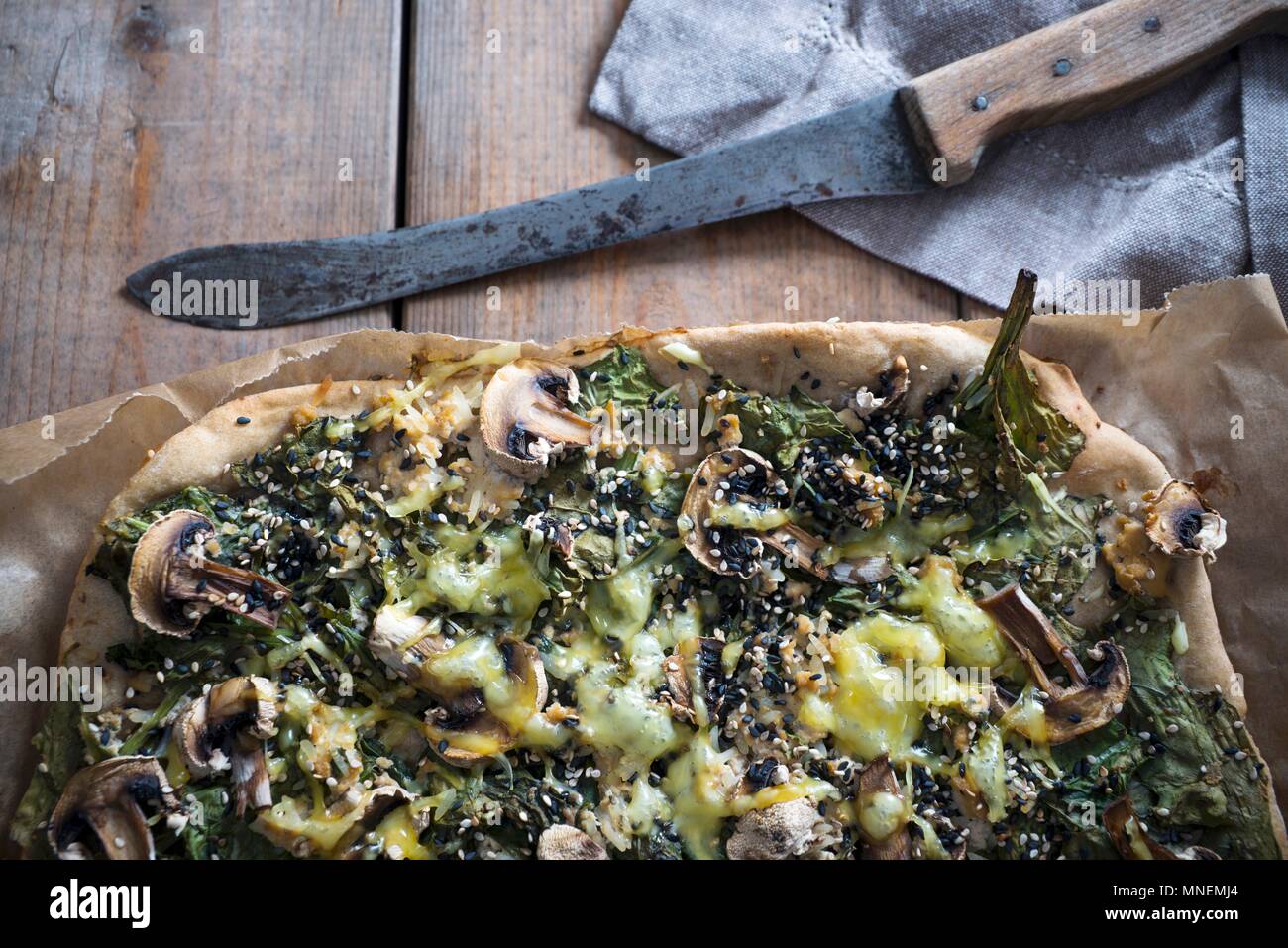 Vegan pizza with tofu, spinach, mushrooms, sesame and a cheese