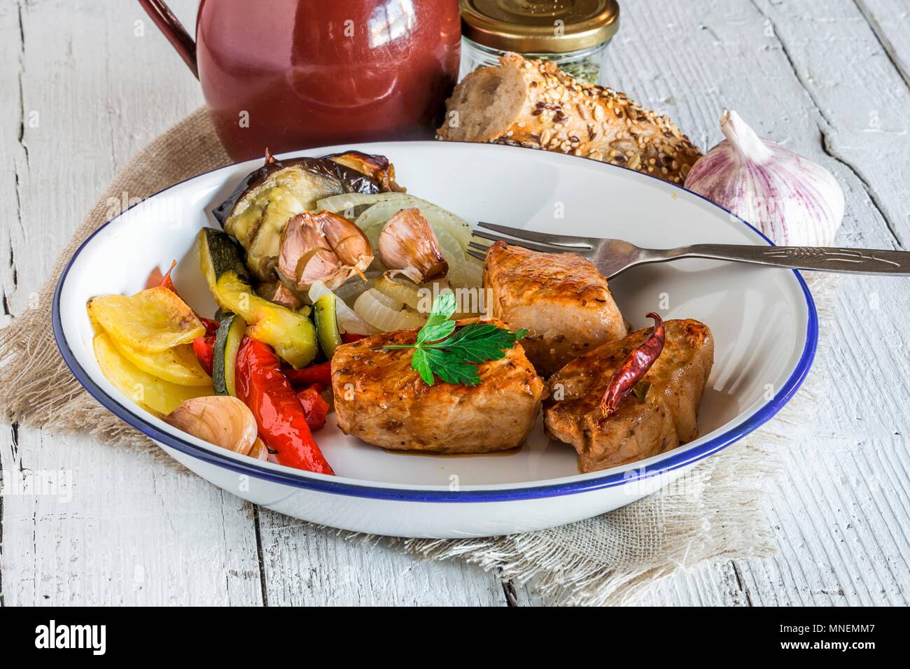 Pork medallions with parsley and vegetables served with a multi-grain baguette Stock Photo