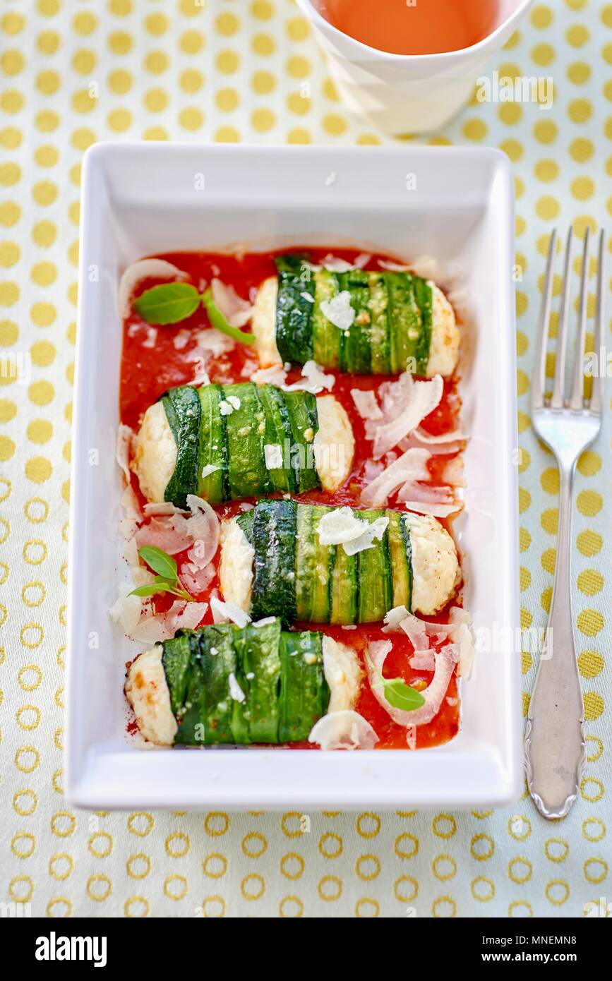 Zucchini rolls with fresh cheese filling on tomato sauce Stock Photo