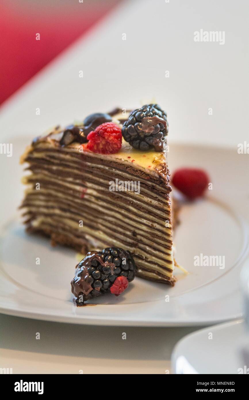 A slice of pancake cake with berries and chocolate sauce Stock Photo
