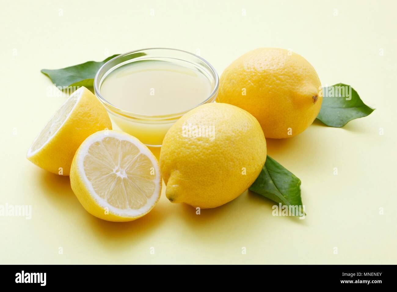 A bowl of lemon juice and fresh lemons Stock Photo