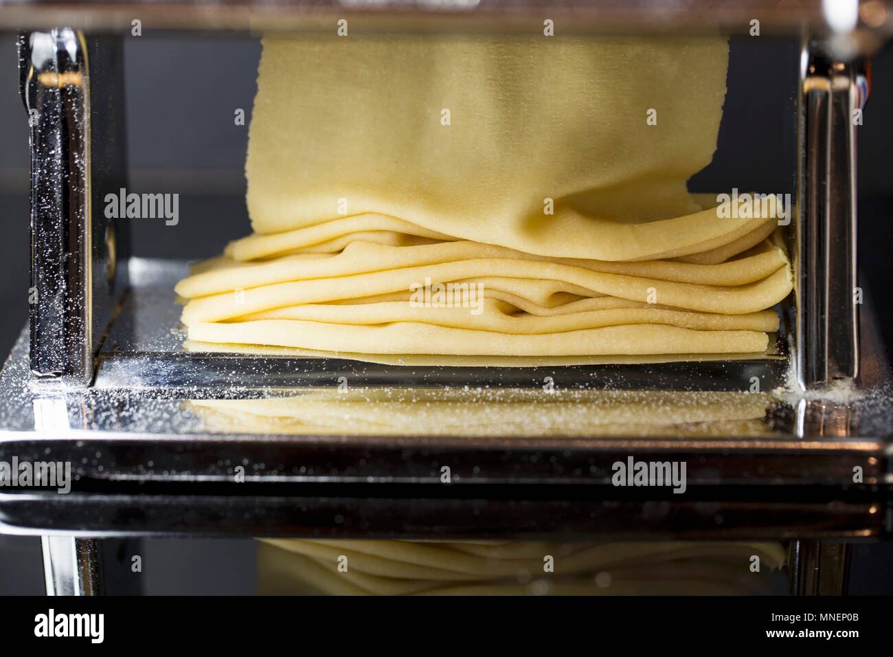 Fresh pasta dough being passed through a pasta machine Stock Photo