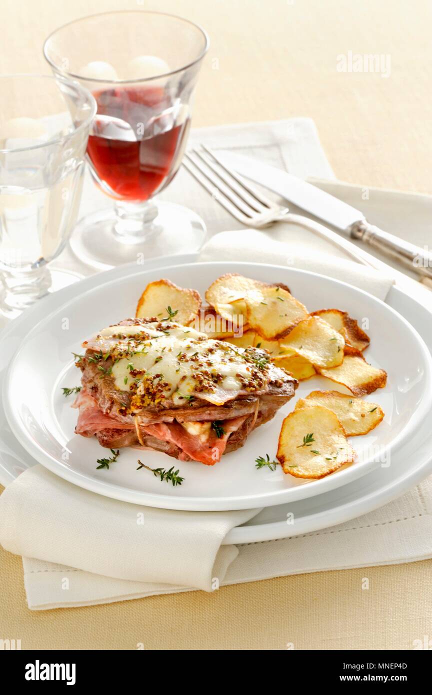 Leaflet with ham and Greyerzer cheese served with crispy potato chips Stock Photo