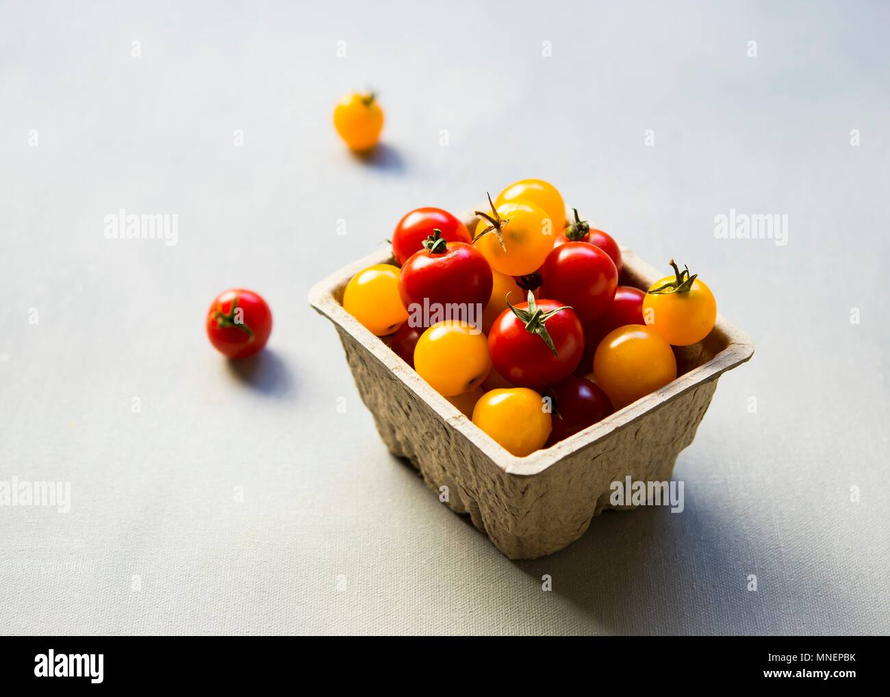 Red and yellow cherry tomatoes in a cardboard container Stock Photo - Alamy