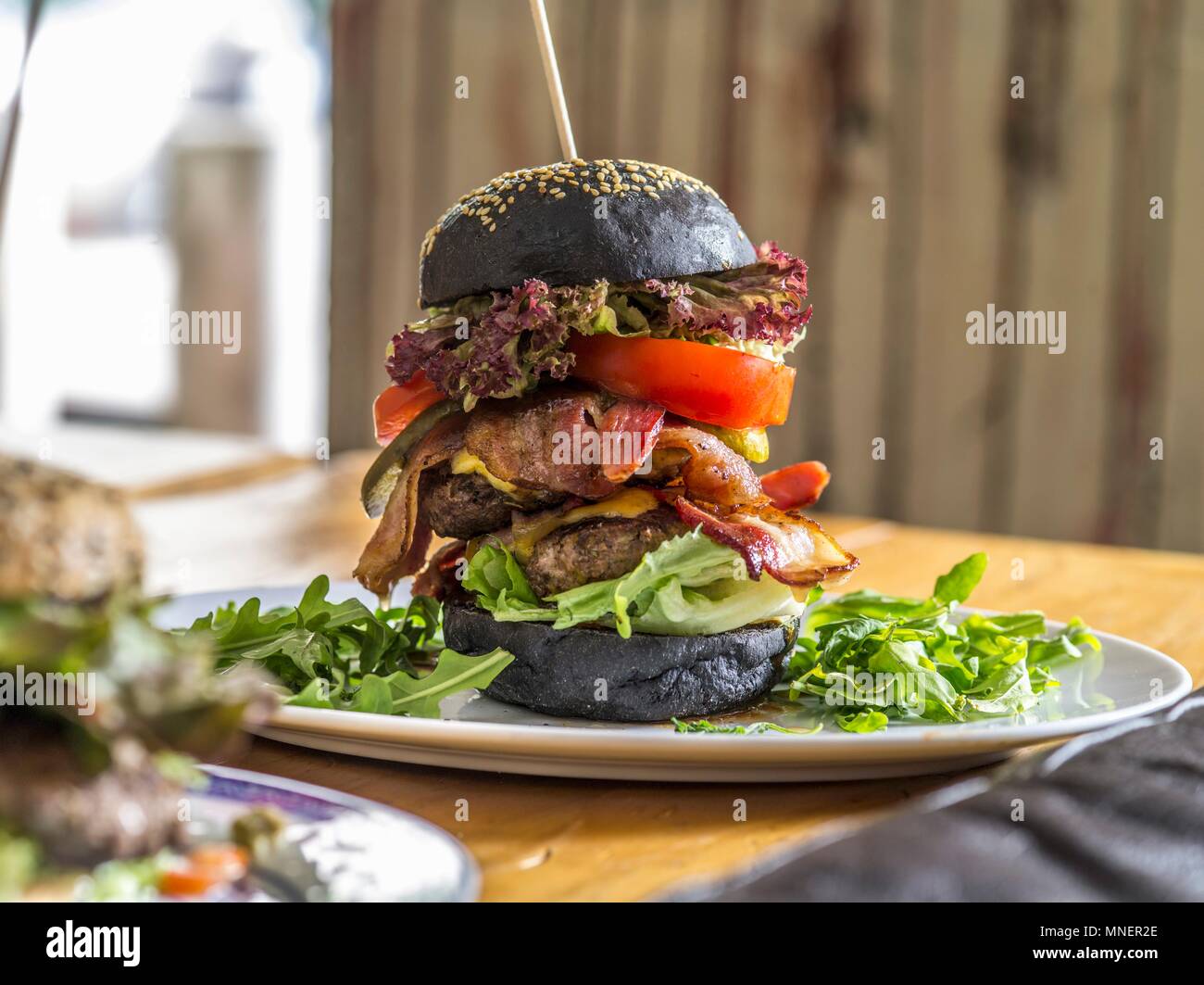 A black bread double burger with bacon, lettuce and cheese on a wooden skewer Stock Photo