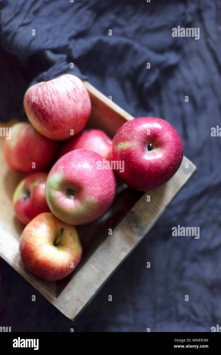 Pink apples in a wooden box on a dark grey fabric Stock Photo