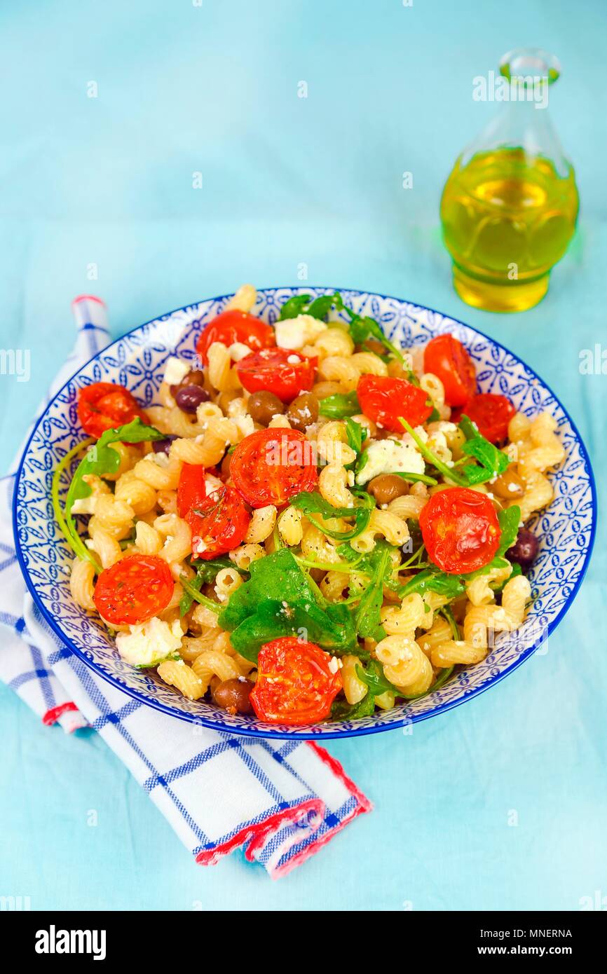 Pasta with steamed tomatoes, feta cheese, olives and rocket Stock Photo