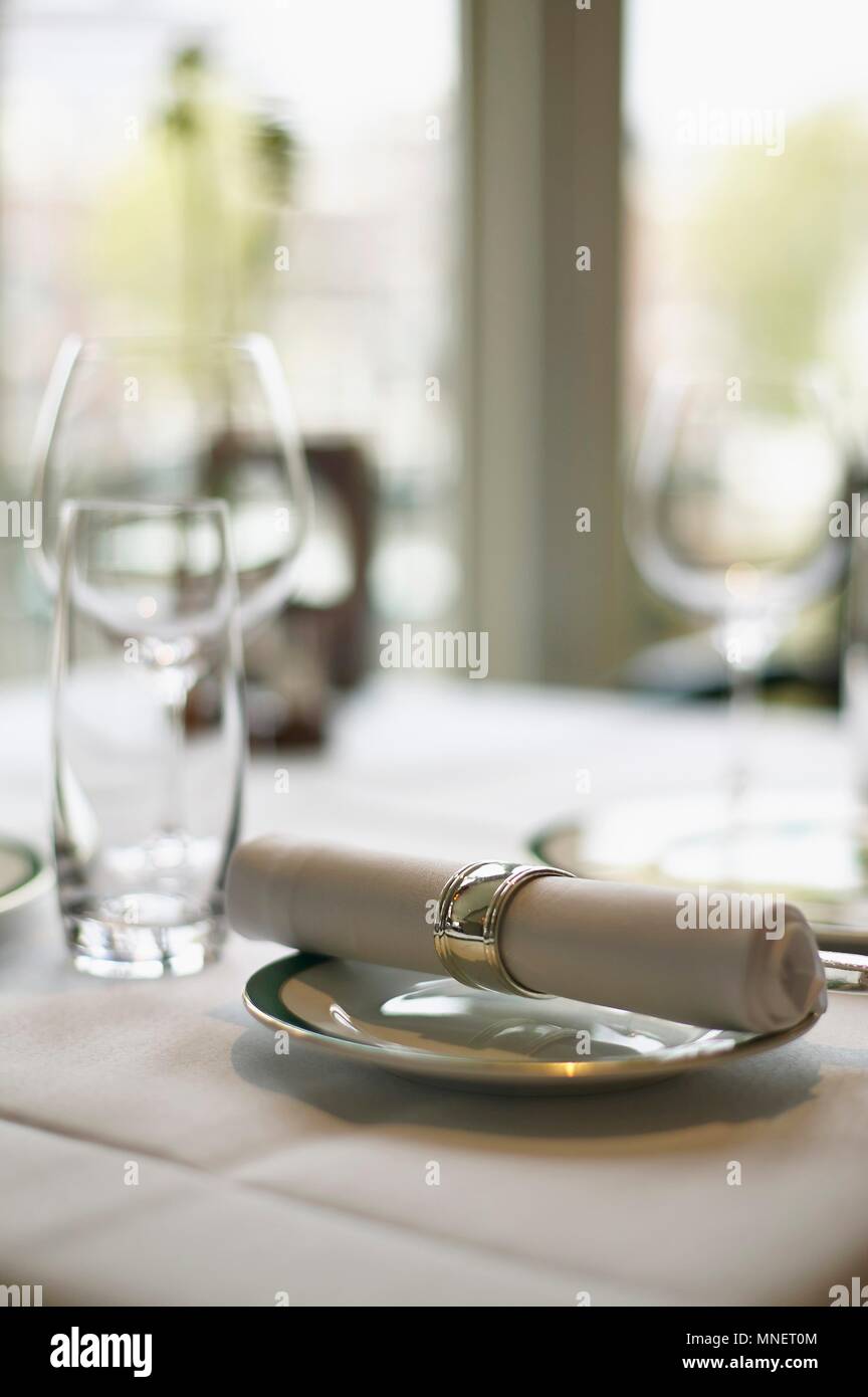 A fabric napkin on a plate and empty glasses on a table in a restaurant Stock Photo