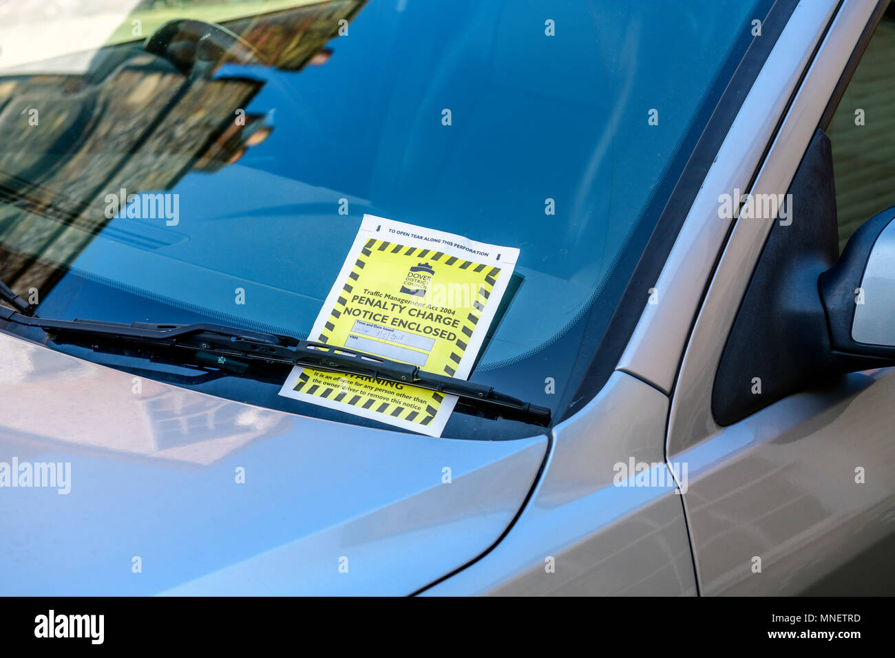Parking penalty charge notice under car windshield wipers Stock Photo