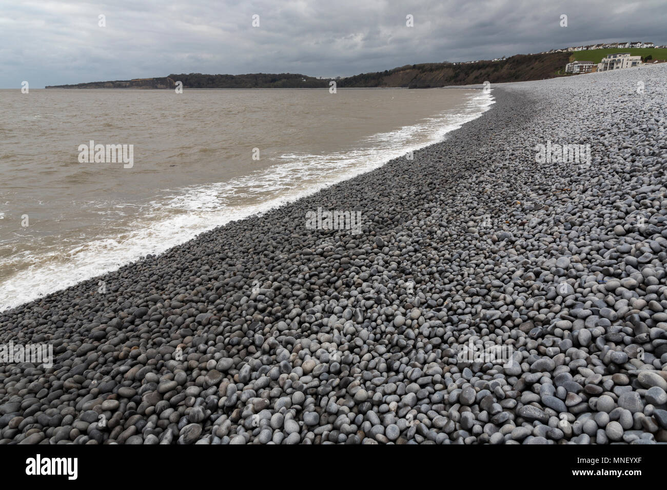 Cobbles on beach with brown silty water in sea, Cold Napp, Barry, Wales, UK Stock Photo