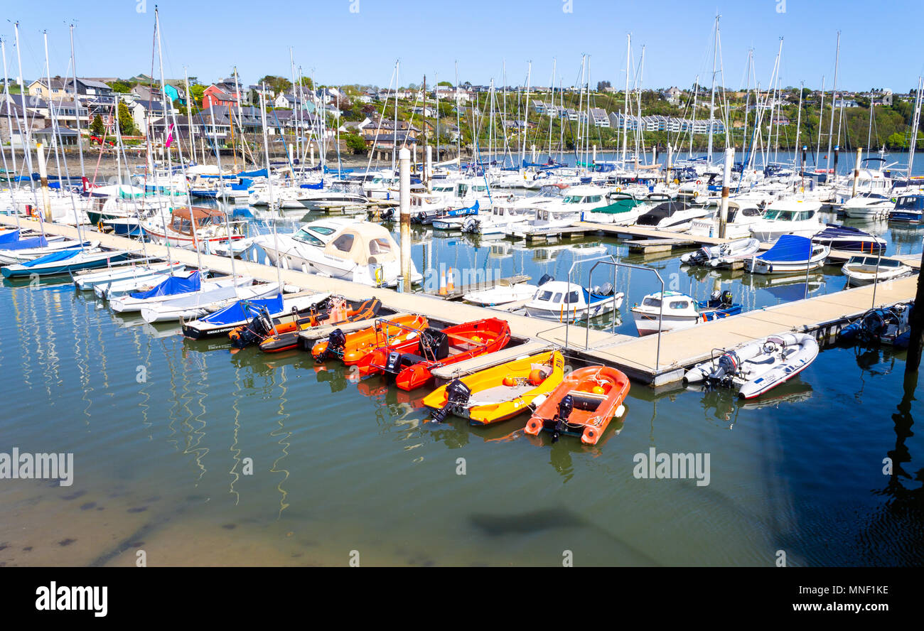 pontoon with yachts and boats moored up with brightly coloured houses on the hillside in the background at kinsale ireland yacht club Stock Photo