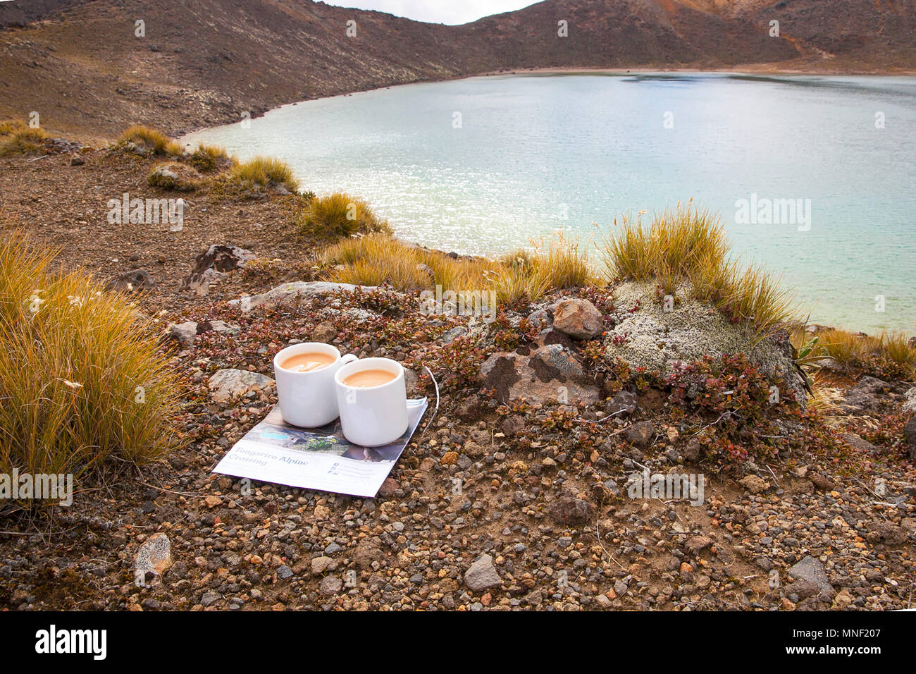 Two mugs of tea beside a crater lake Stock Photo