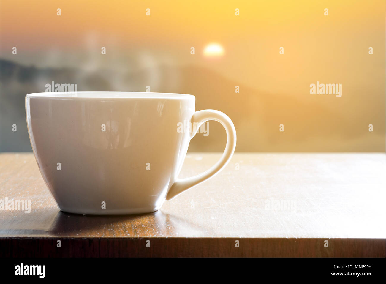 Hot coffee in white cup on wooden table in the morning when sunrise