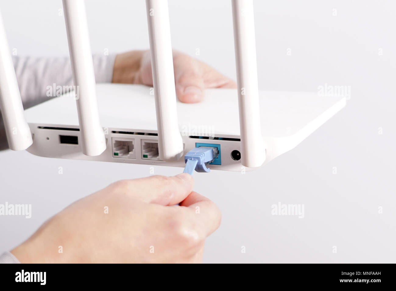 The back view of router showing the lan internet port, and the hand is  pluging in the land cable on a white router Stock Photo - Alamy