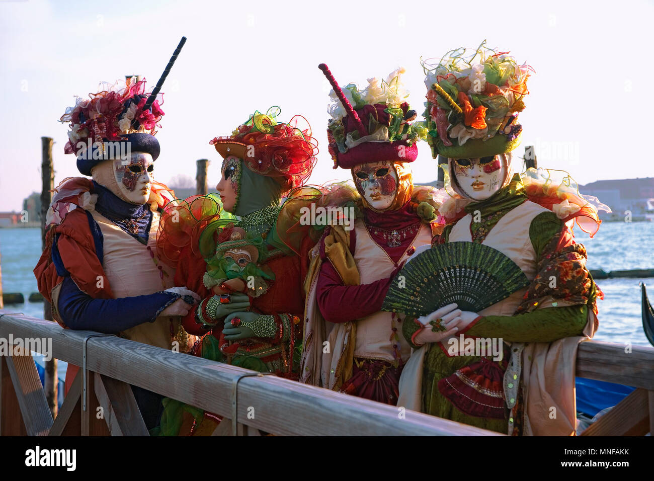 Molo San Marco, Venice, Italy: masked revellers pose in front of the Basin of St Mark Stock Photo