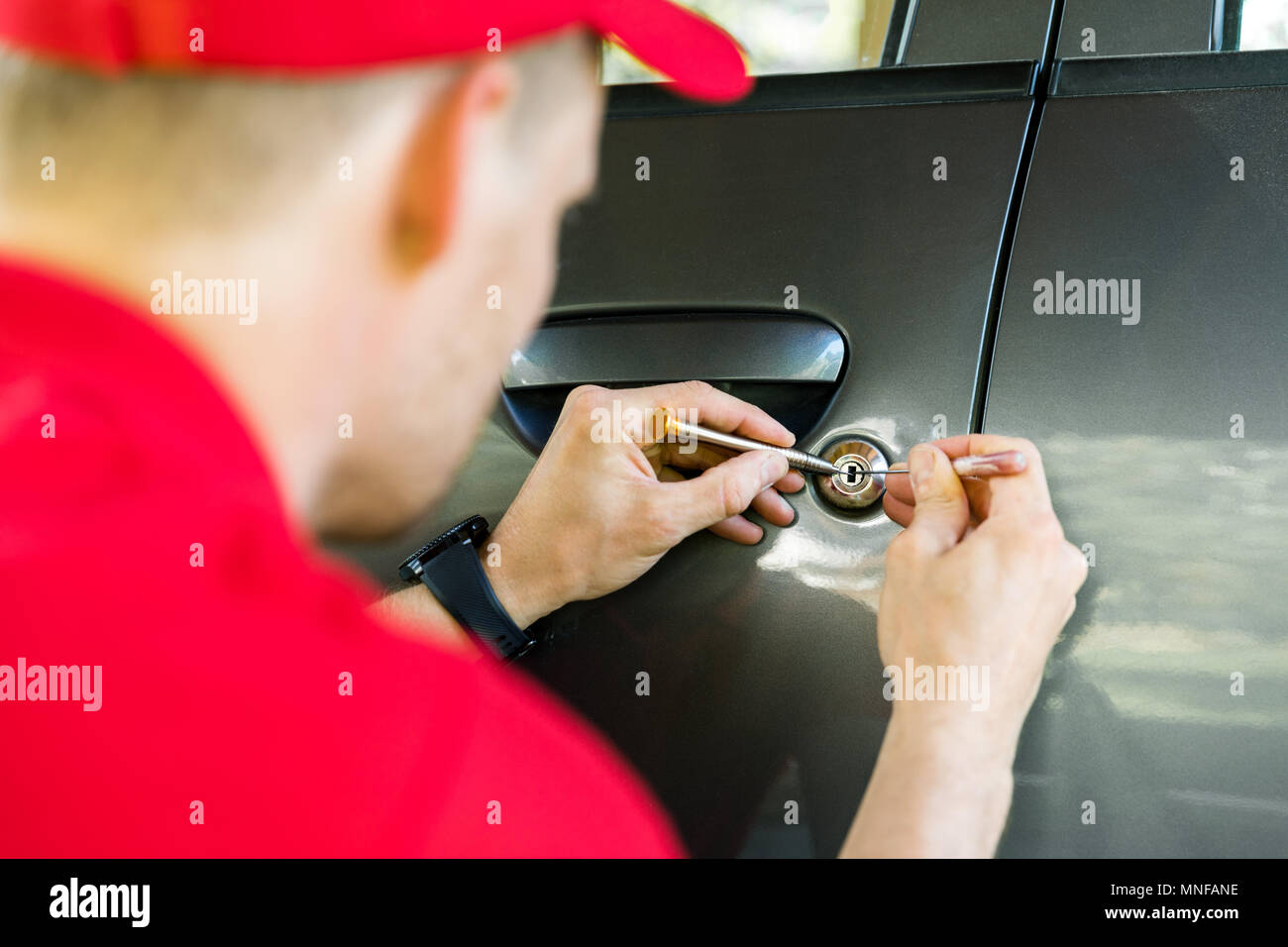 locksmith opening car door with lockpicker Stock Photo
