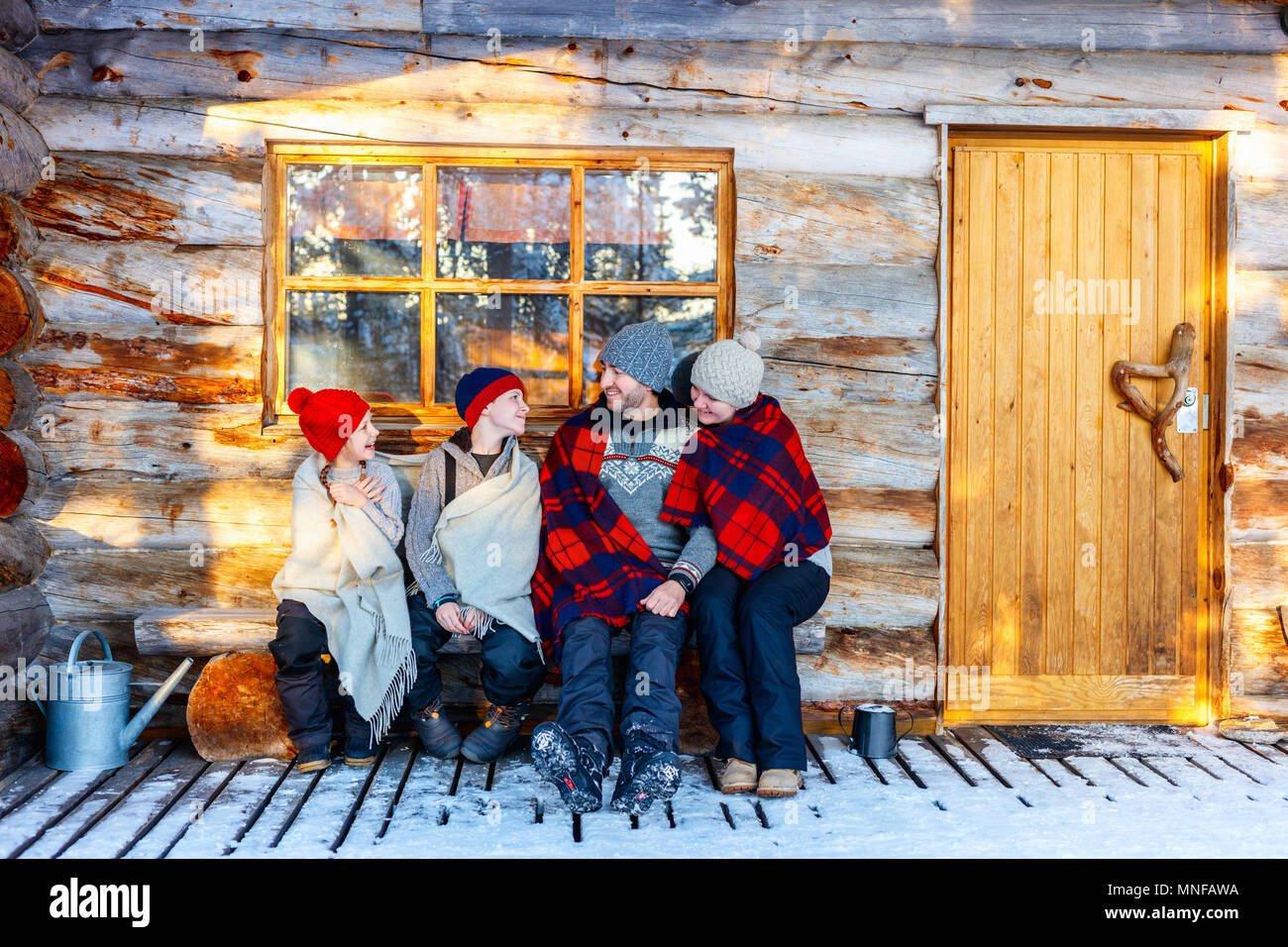 Family With Kids Outdoors On Beautiful Winter Day In Front Of Log