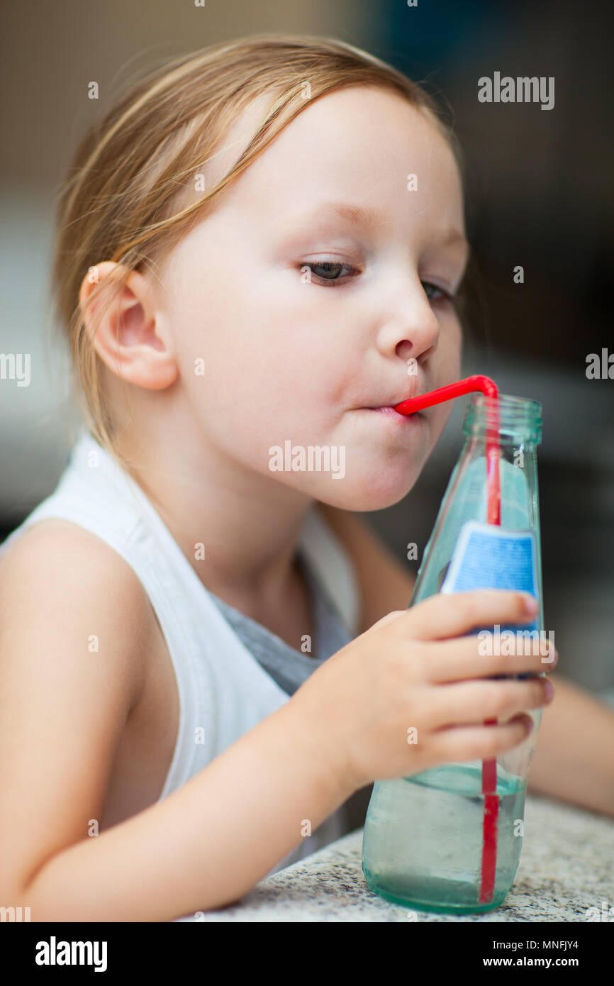 Adorable little girl drinking water from a bottle using a straw Stock Photo