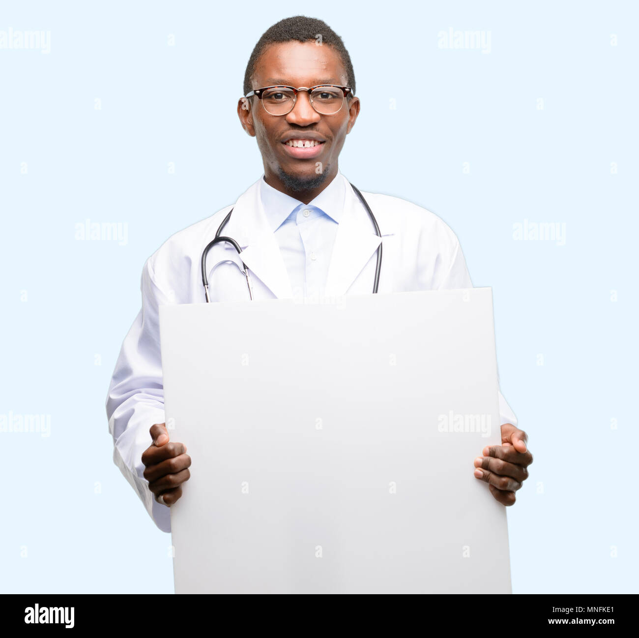 Young black doctor, medical professional holding blank advertising banner, good poster for ad, offer or announcement, big paper billboard Stock Photo