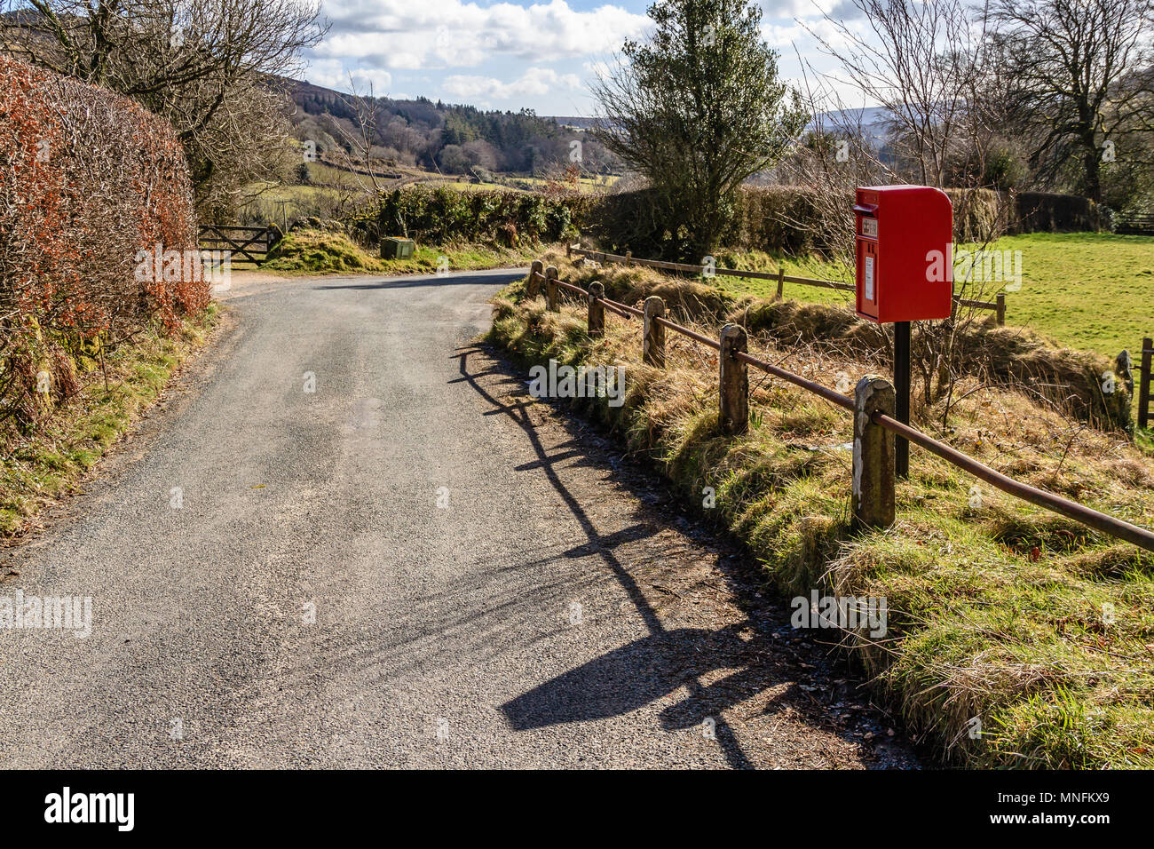 Red postbox on a quiet rural road. Dartmoor, Devon. Feb 2018. Stock Photo