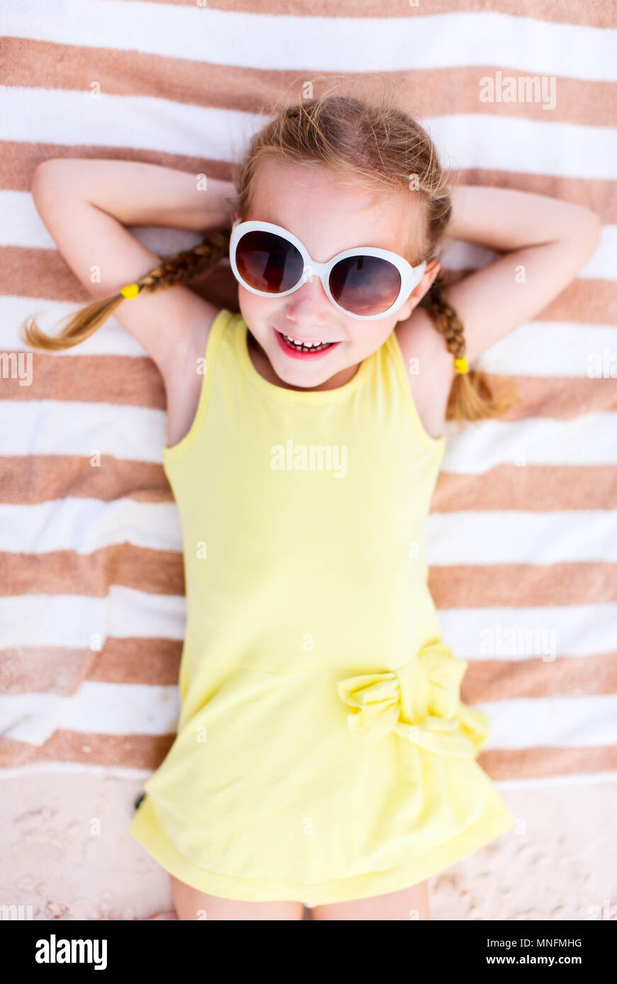 Adorable little girl lying on a beach towel during summer vacation