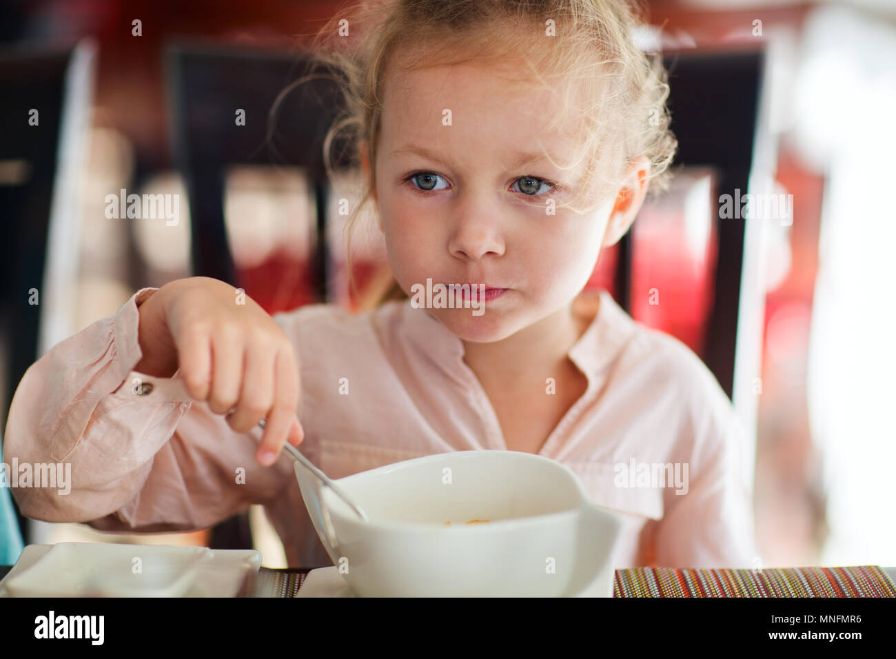 Adorable little girl eating breakfast in restaurant Stock Photo