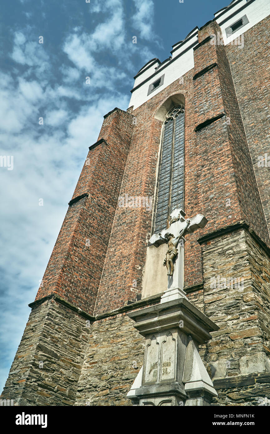 Cross and facade of a medieval defensive church in the Gothic style in Paczkow Stock Photo