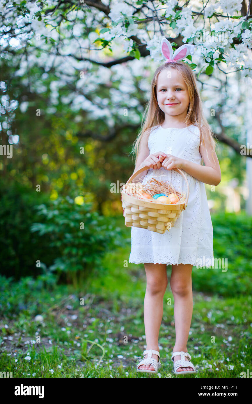 Adorable little girl wearing bunny ears holding a basket with Easter ...