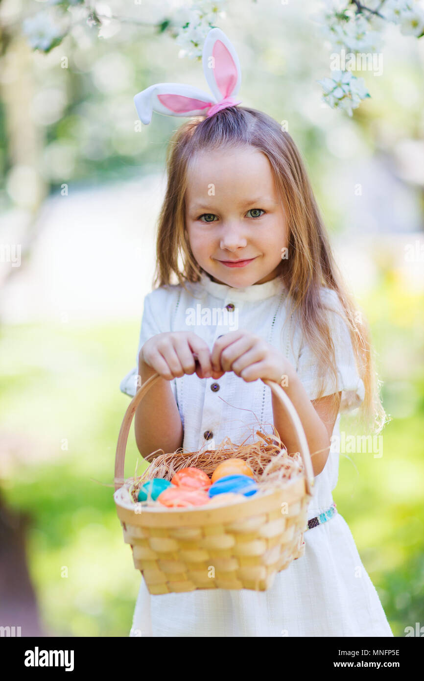 Adorable little girl wearing bunny ears holding a basket with Easter ...