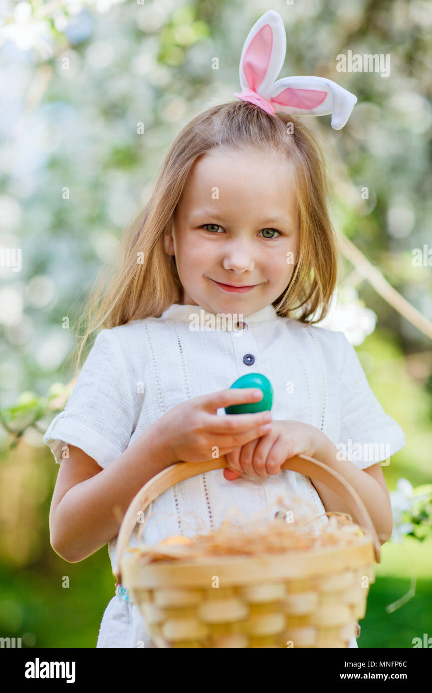Adorable little girl wearing bunny ears holding a basket with Easter ...