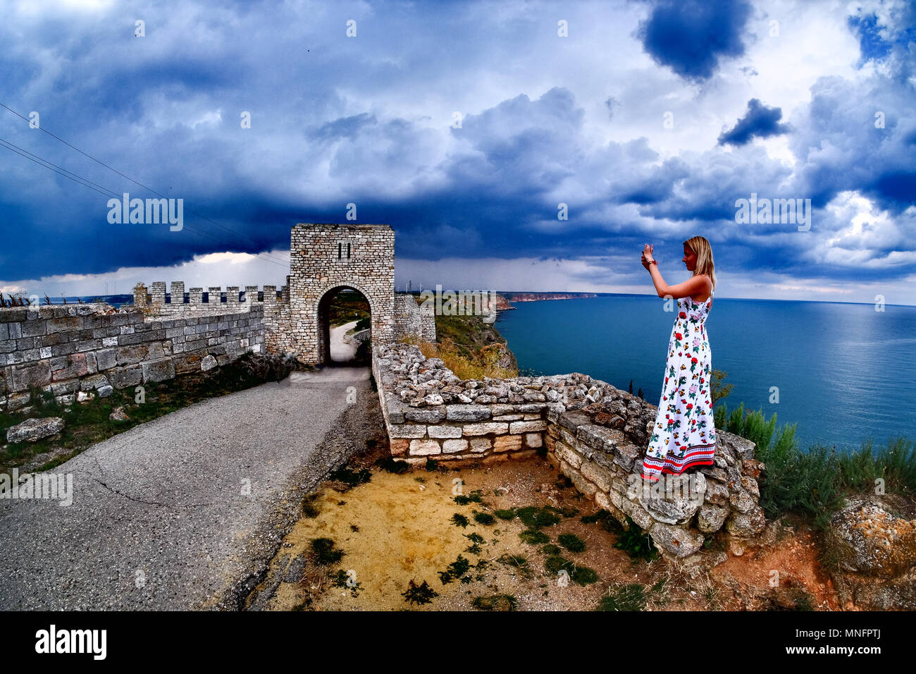 Woman taking pictures at Cape Kaliakra, Bulgaria, Black Sea. Old abandoned fortress by the sea. Stock Photo