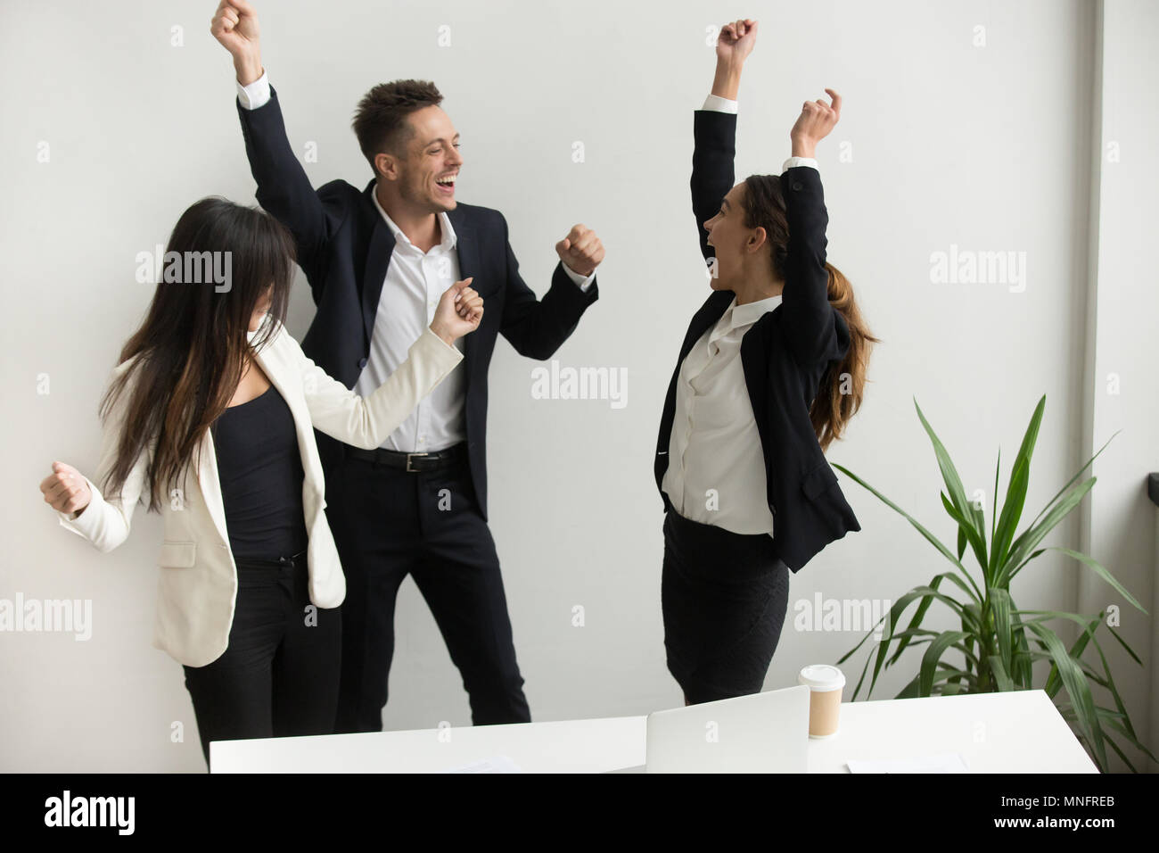 Excited colleagues celebrating online win raising hands Stock Photo