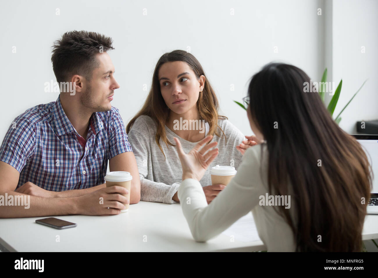 Couple looking at each other doubting offer Stock Photo